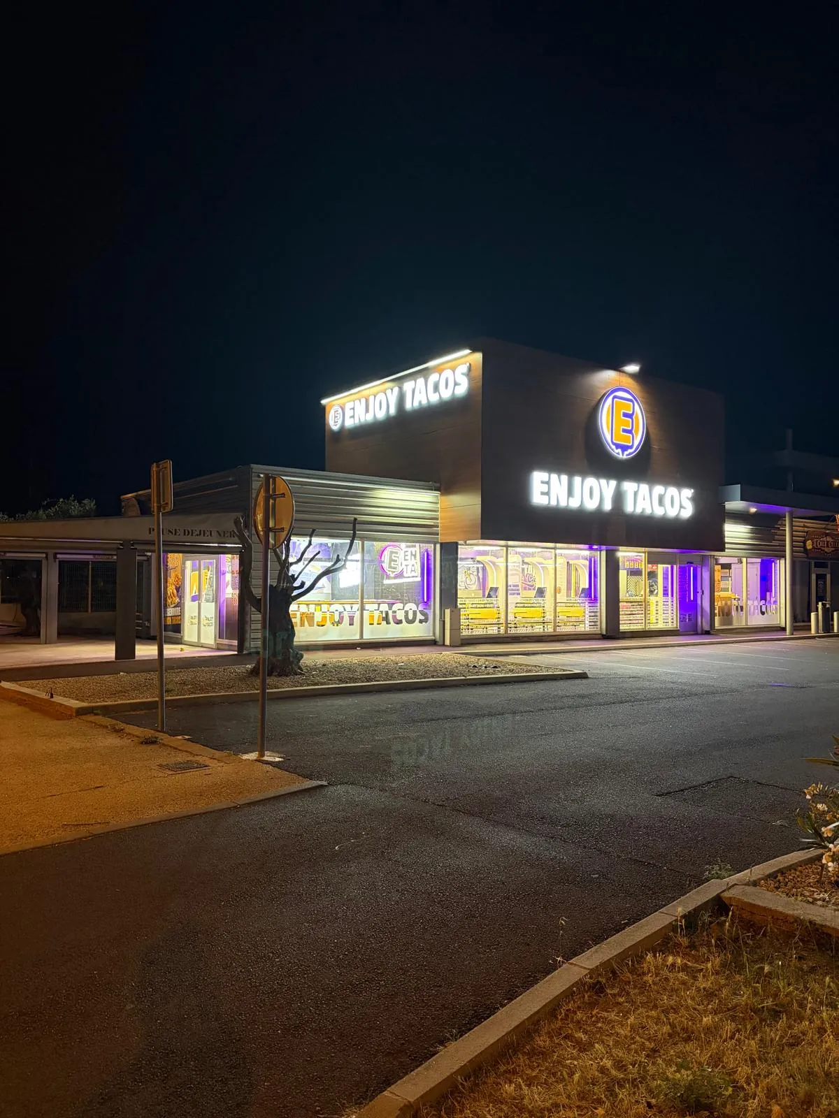Façade d’un restaurant Enjoy Tacos de nuit, enseigne lumineuse et intérieur éclairé